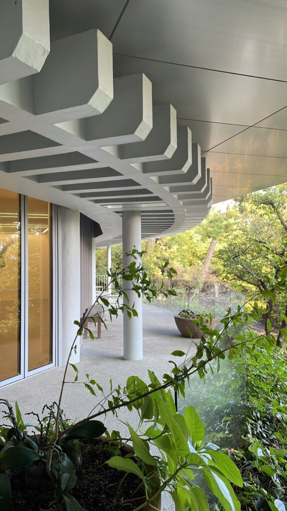 Curved architectural balcony and green trees at Johyun Gallery Busan entrance