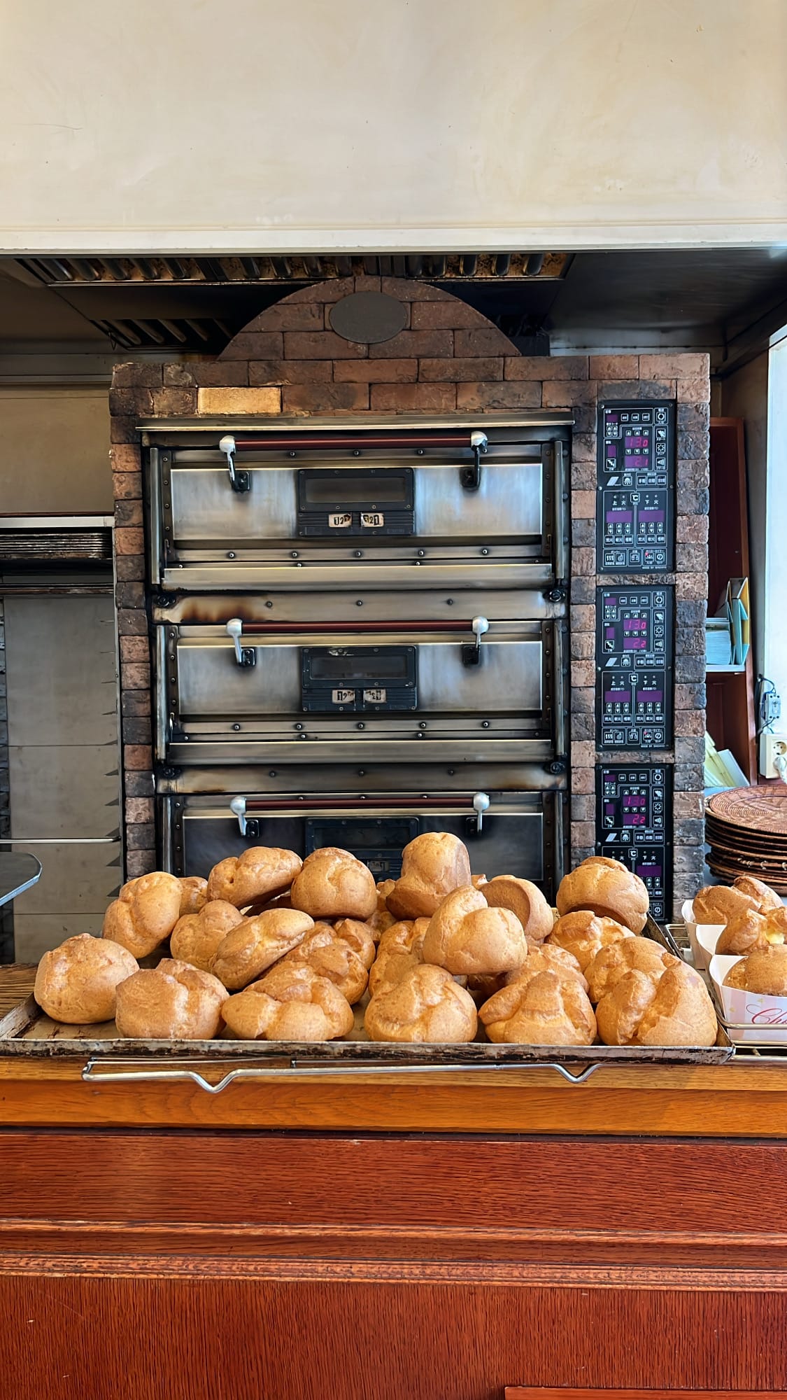 Freshly baked giant choux cream pastries piled in front of the brick oven