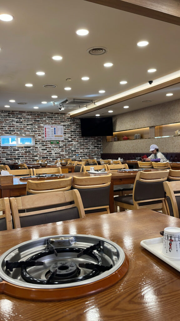 Spacious interior of the restaurant featuring exposed brick wall design and wooden dining tables.