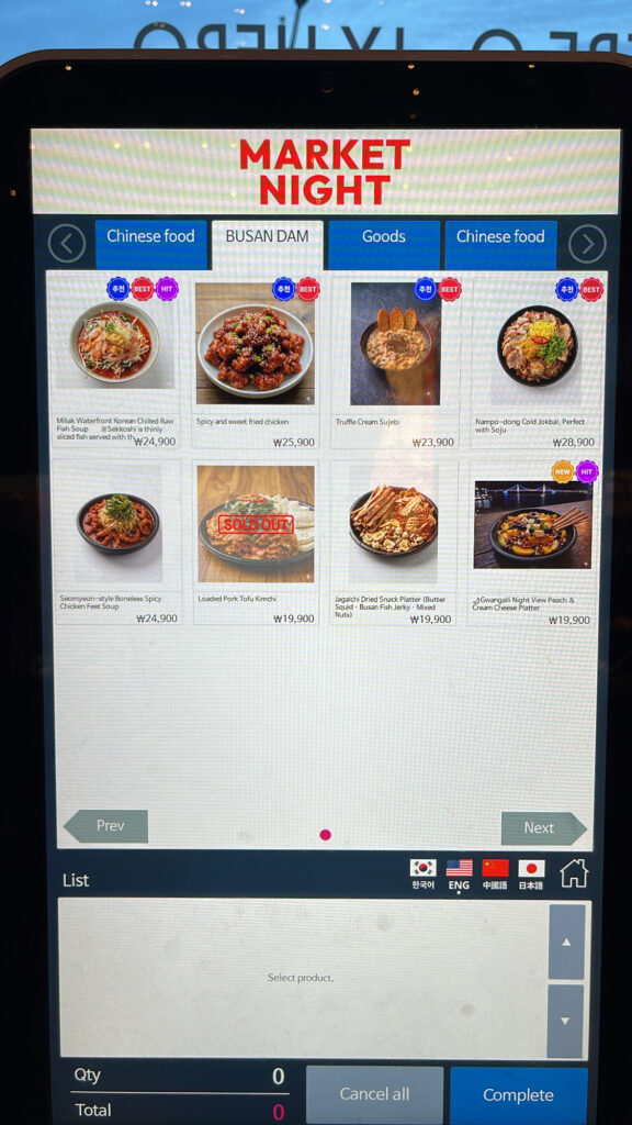 Digital kiosk screen showing local Busan snacks and drinks at Millac The Market at Night