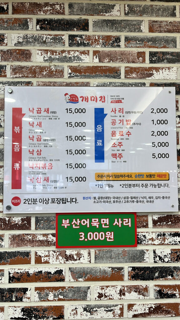 Wall menu board displaying prices for Nakgopsae and options to choose mild, medium, or spicy flavor levels.