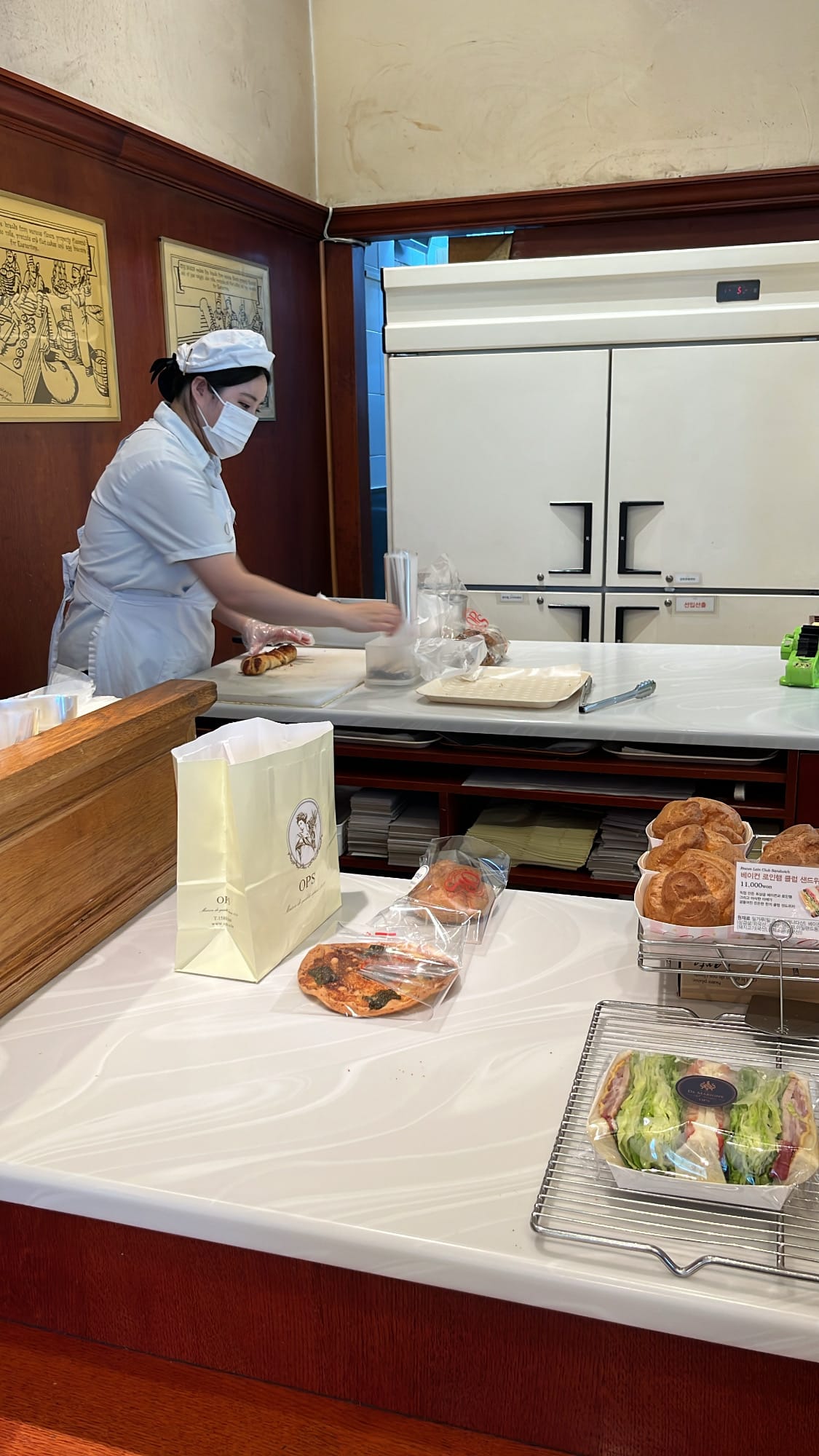 Bakery staff wrapping freshly purchased pastries at OPS checkout counter