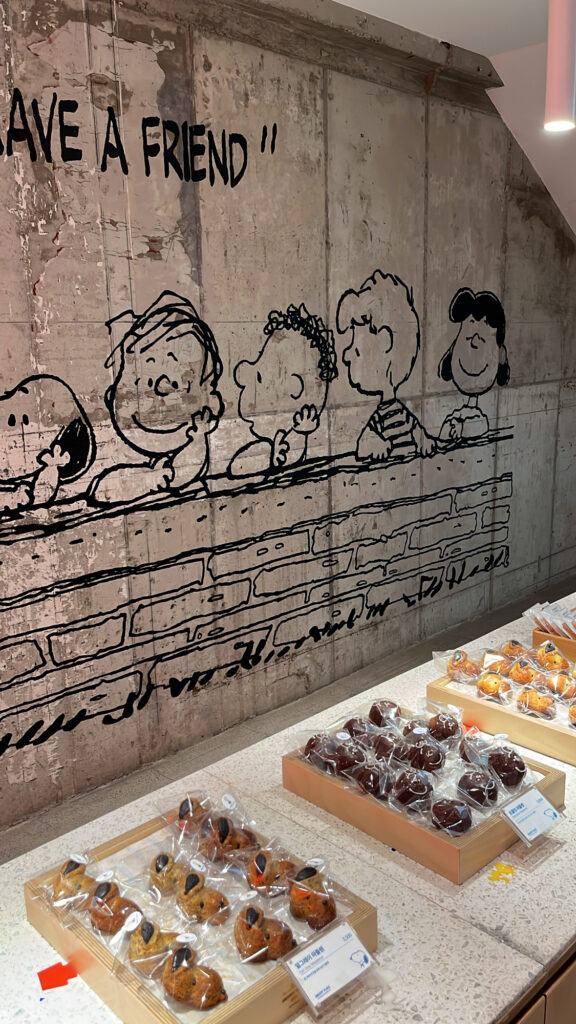 Peanuts character comic strip mural behind the dessert display in Snoopy Place Busan