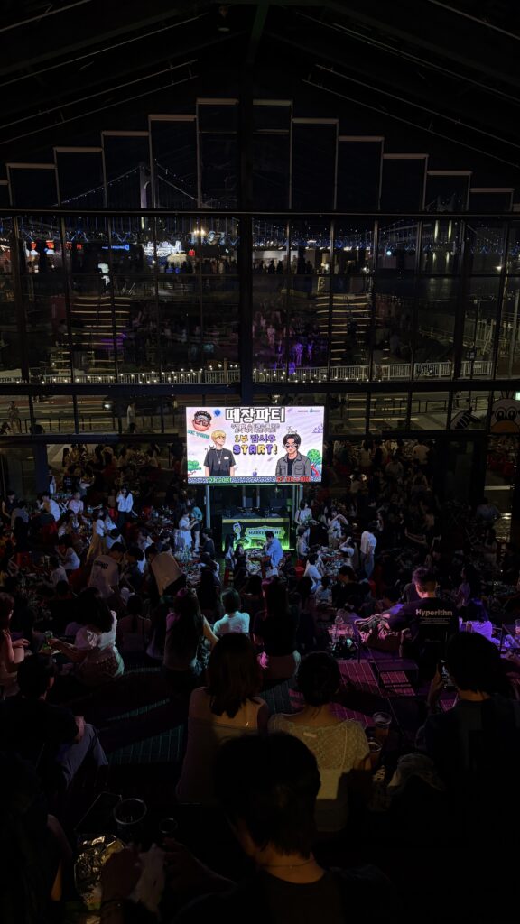 verview of the lively crowd and DJ stage from the top stairs at Millac The Market at Night