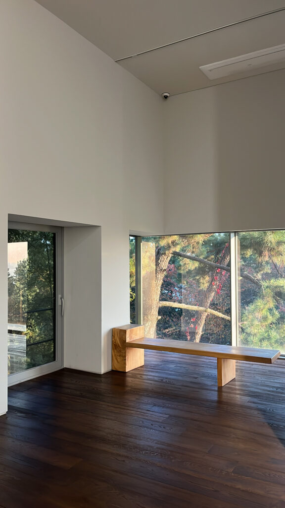Wooden bench and large window overlooking nature at Johyun Gallery Busan