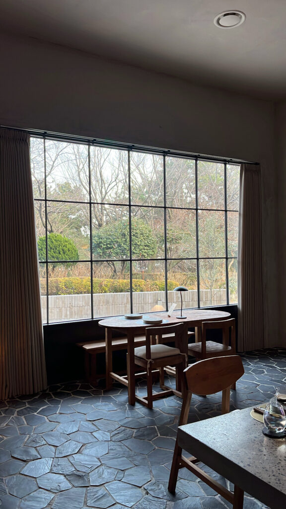 Seated dining area by the large window overlooking scenic Dalmaji-gil at Moment Local Busan