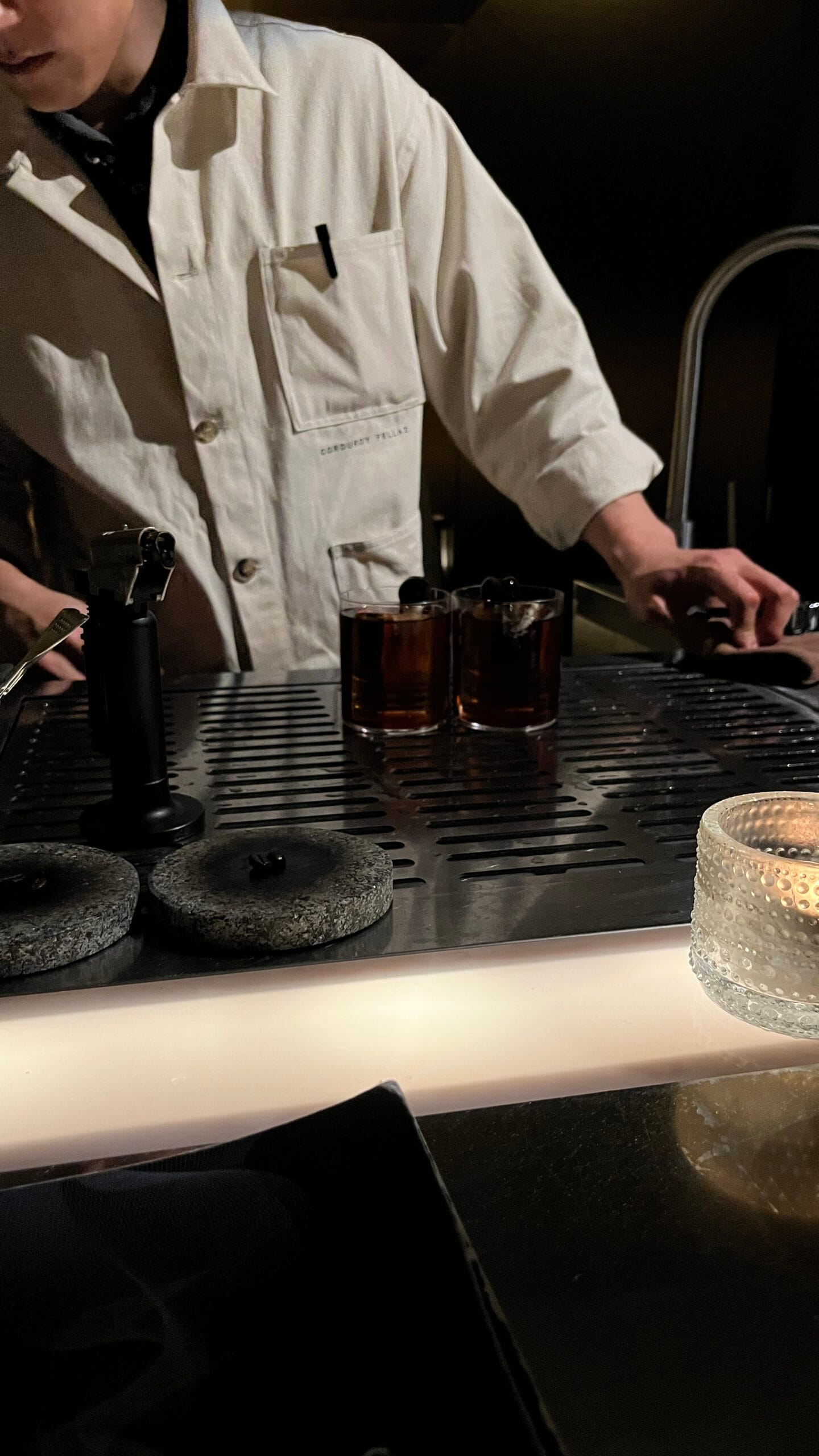 Two completed signature cocktails placed on the bar prep station
