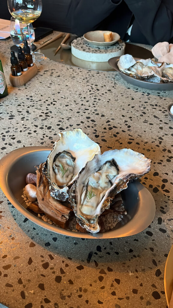 Plated fresh triploid giant oysters with garnishes at Moment Local Busan oyster bar