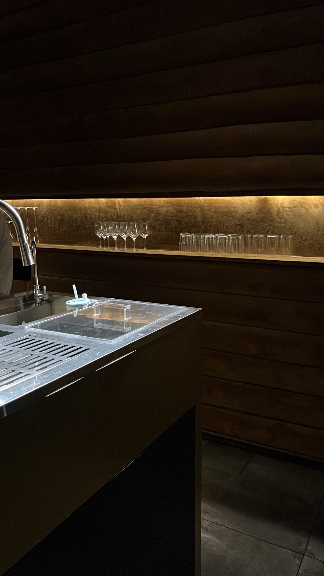 Close-up of polished cocktail glasses aligned above the workstation