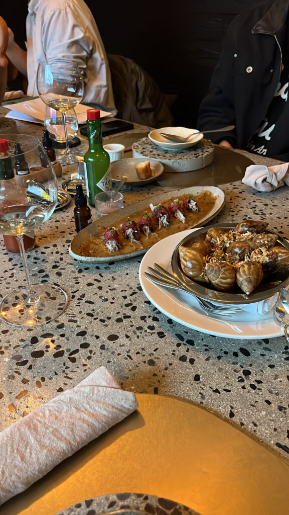 Escargot dish and fresh appetizers served on the terrazzo table at Moment Local Busan