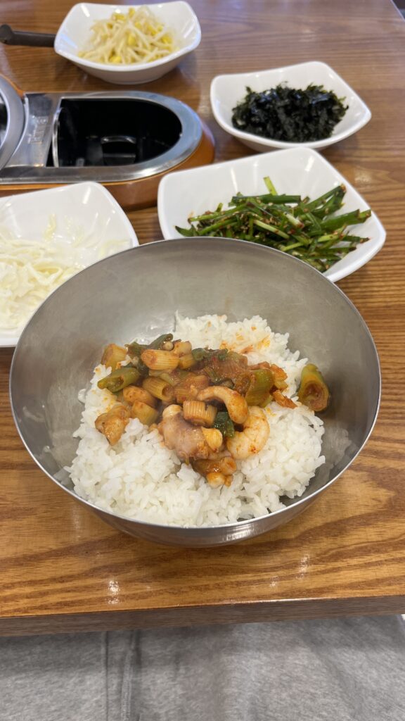 Cooked Nakgopsae served over a warm bowl of white rice, ready to be mixed.