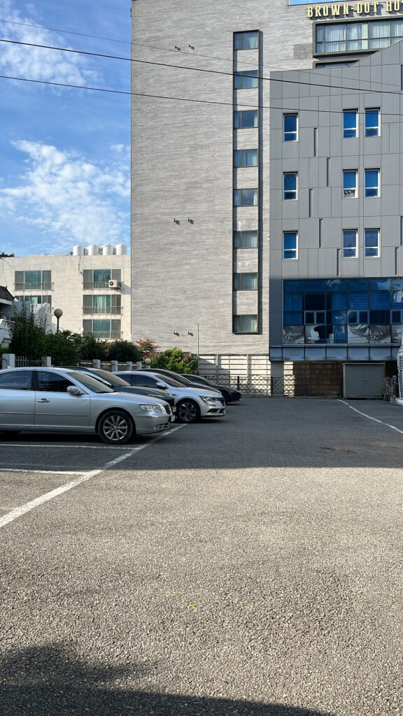 A spacious outdoor parking lot with several parked cars in front of the restaurant building.