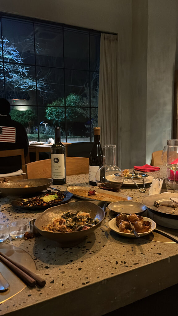 Dining table filled with wine bottles, decanter, and empty plates at Moment Local Busan