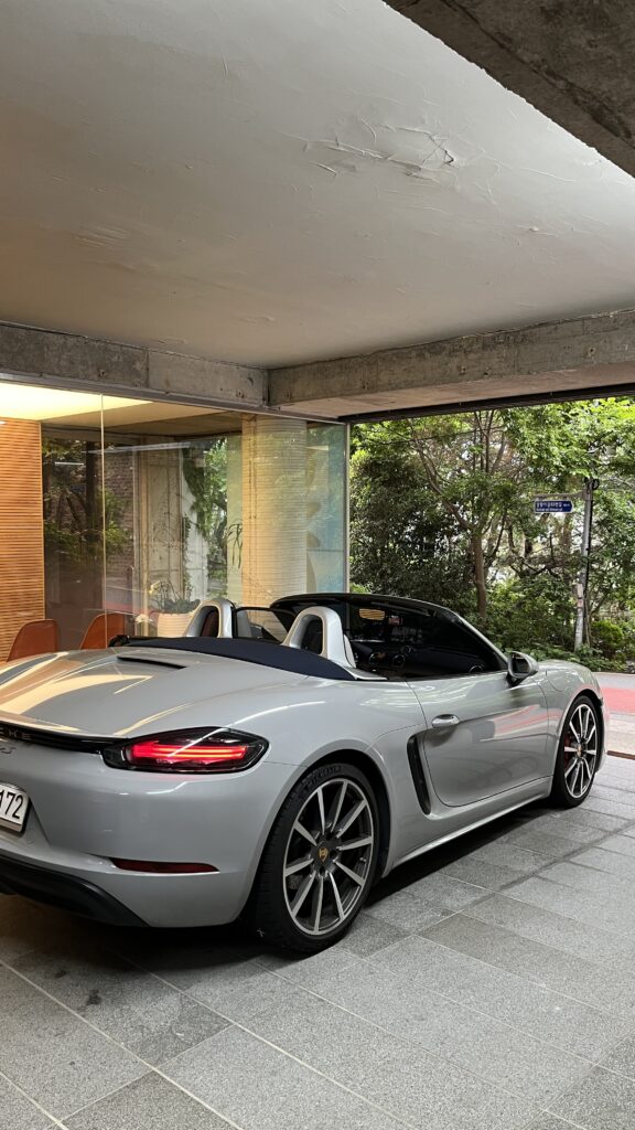 Porsche sports car parked in glass enclosed parking garage at Johyun Gallery Busan