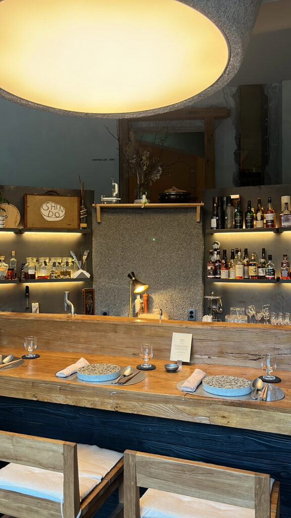 Table setting at the bar counter with liquor shelves at Moment Local Busan