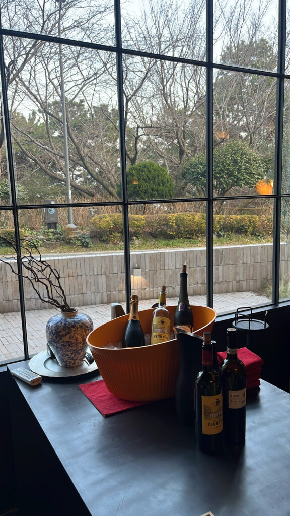 Wine bottle display by the large grid window at Moment Local Busan