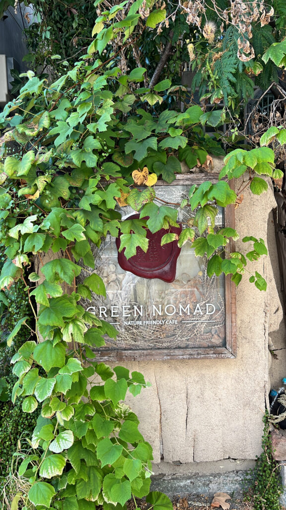 Unique vintage wooden signboard surrounded by green leaves at Green Nomad Busan near Centum City