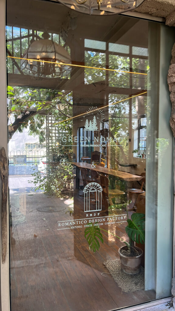 Glass entrance door with botanical decorations at Green Nomad Busan cafe near F1963