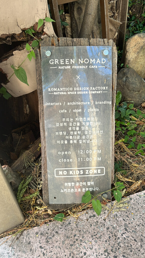 Close-up of welcome sign and glass door at the entrance of Green Nomad Busan plant cafe
