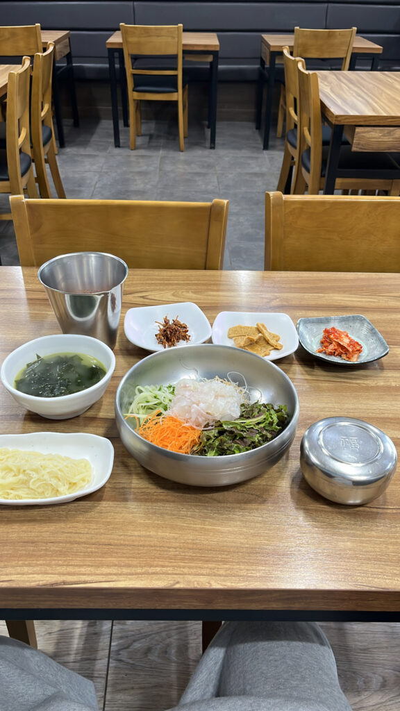 Full table setting with side dishes, noodles, and seaweed soup at Dongchon Mulhoe Busan
