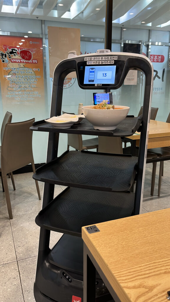 Automated smart serving robot delivering hot noodle bowls to tables at Ebiga Jjamppong Centum