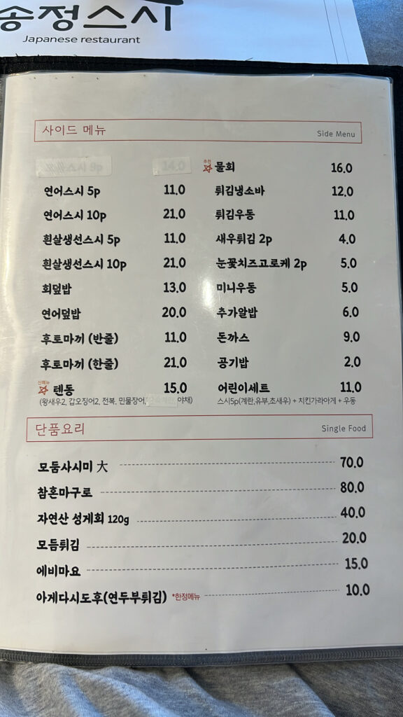 A la carte dishes, fresh seafood sides, and additional food menu board at Songjeong Sushi Busan