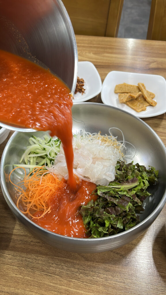 Pouring red icy broth into the cold raw fish bowl at Dongchon Mulhoe Busan