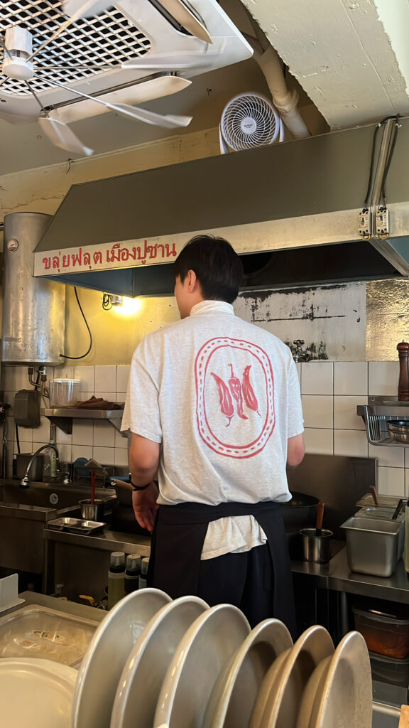 Chef preparing authentic Thai dishes in the open kitchen viewed from the bar counter