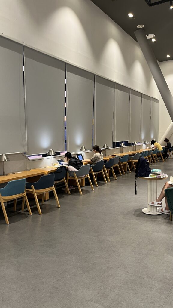 Long window-facing study counter with desk lamps at Busan Cinema Center Library