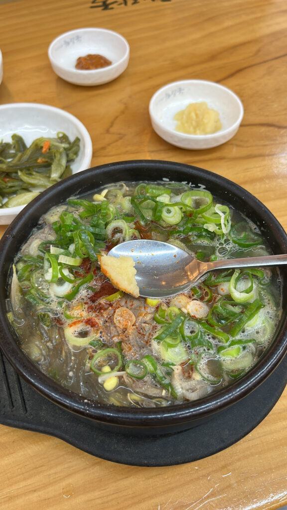 Adding minced garlic topping to spicy Jeju style beef soup broth