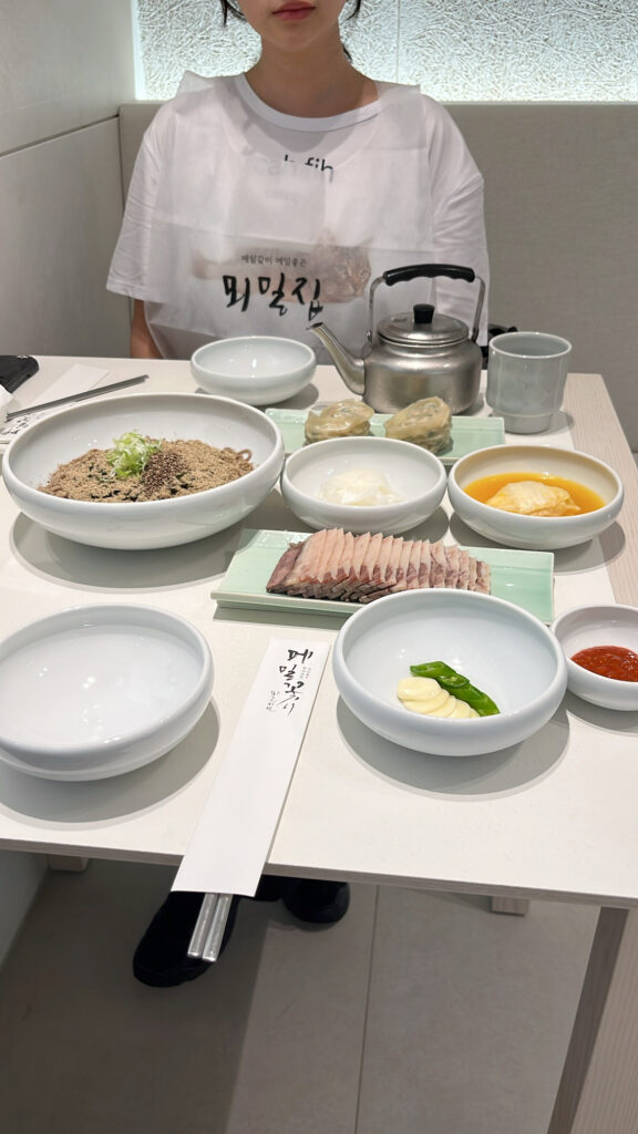 Full table setting with perilla oil makguksu, boiled pork, and dumplings at Moemiljip Busan