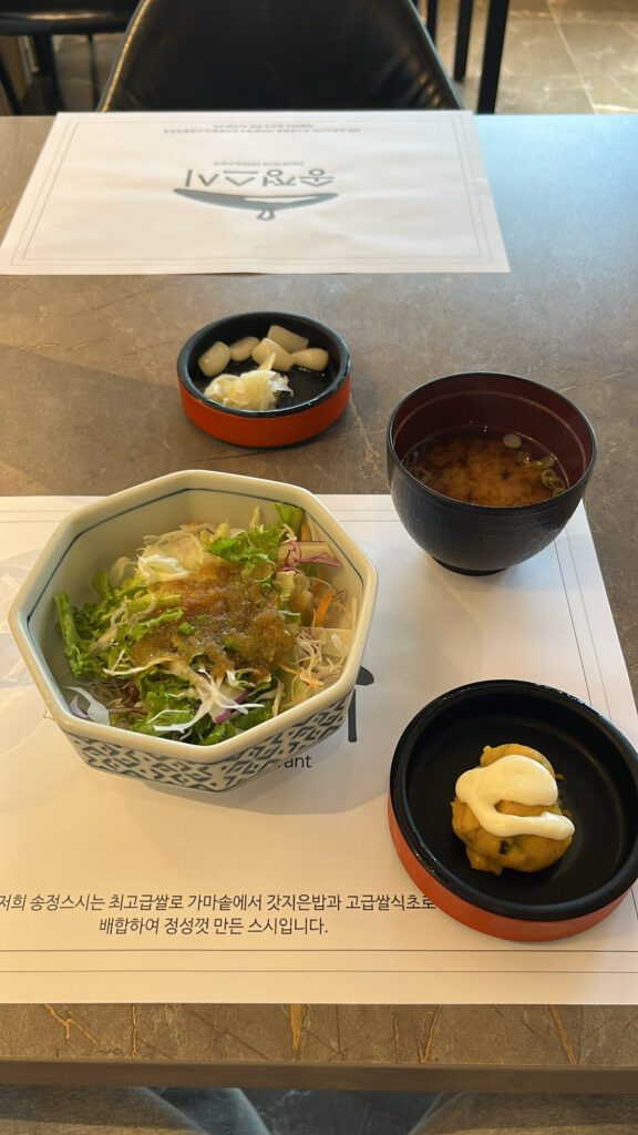 Fresh appetizer salad, warm miso soup, and traditional side dishes served at Songjeong Sushi Busan