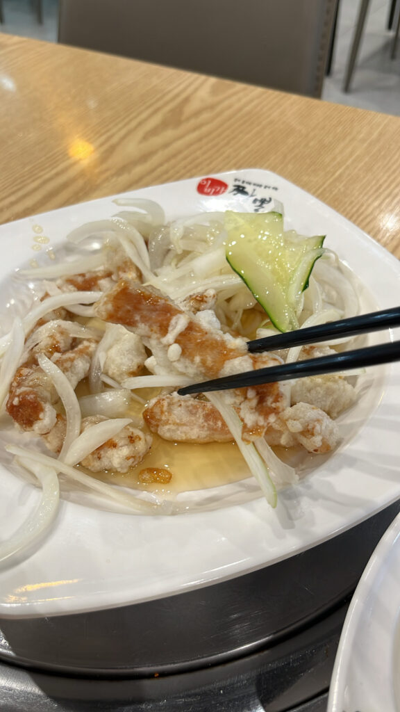 Close-up of chewy glutinous rice sweet and sour pork (Tangsuyuk) topped with fresh onions