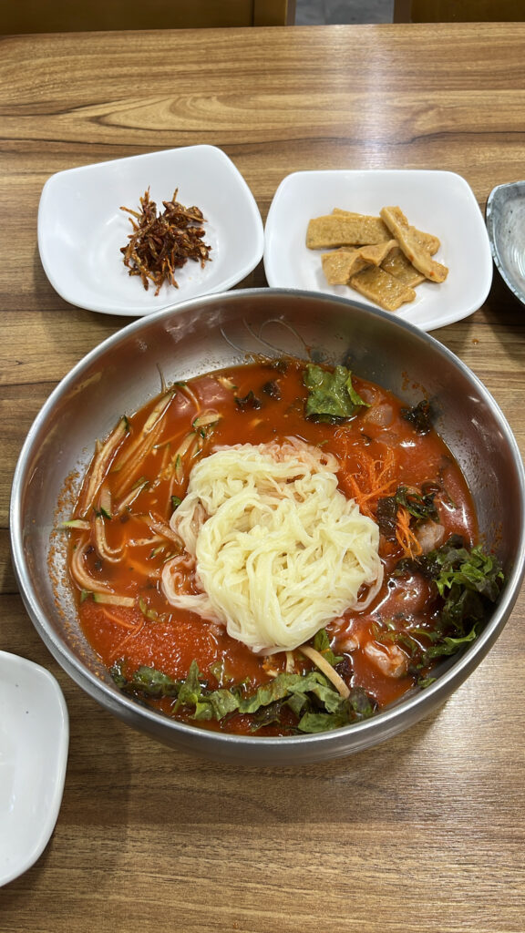 Mixing thin noodles into the cold raw fish soup at Dongchon Mulhoe Busan