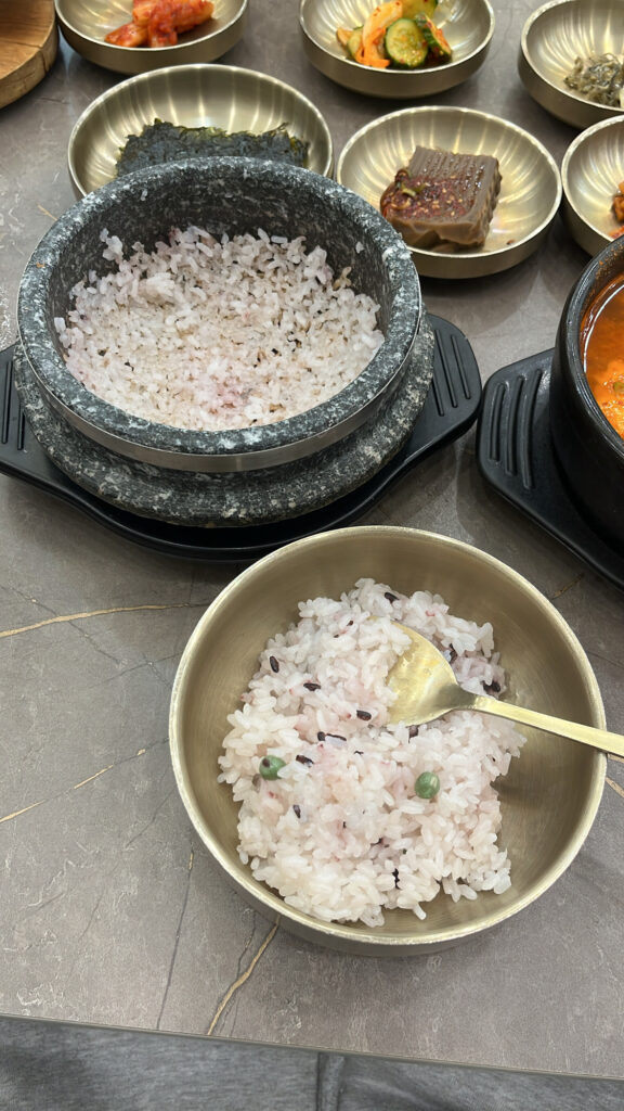 Scooping fresh rice from stone pot into a bowl at Wandduk Sundubu Centum City