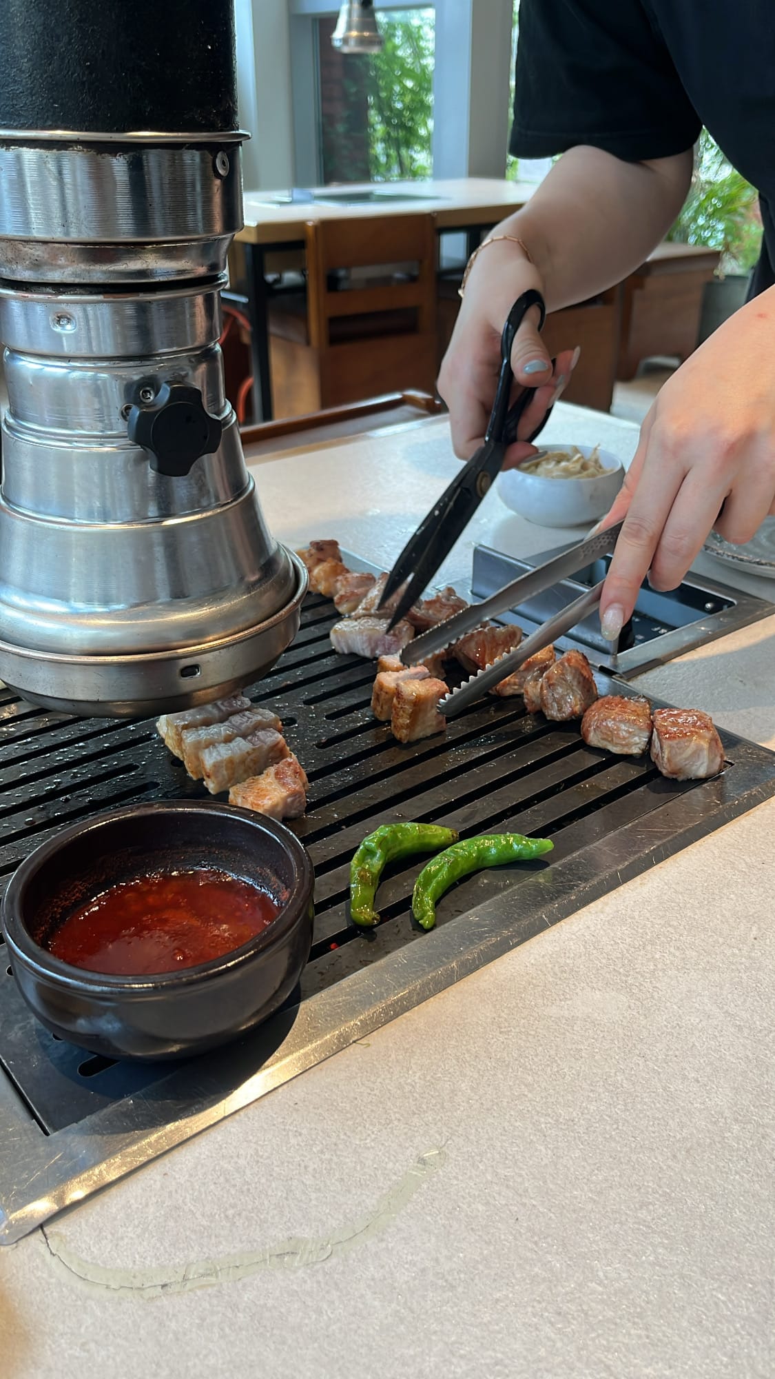 Friendly restaurant staff professionally slicing and grilling pork at Gohasoon Gwangalli