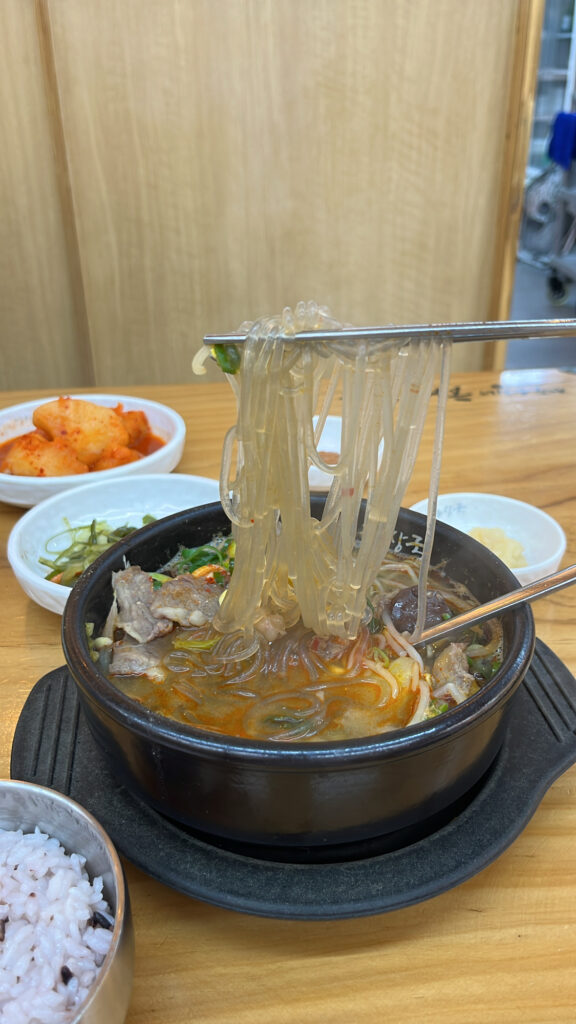 Chewy glass noodles lifted from spicy Jeju Eunhuine beef soup bowl