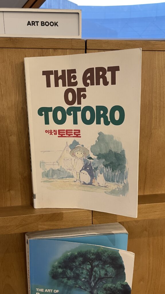 The Art of Totoro animation art book displayed on the wooden shelf