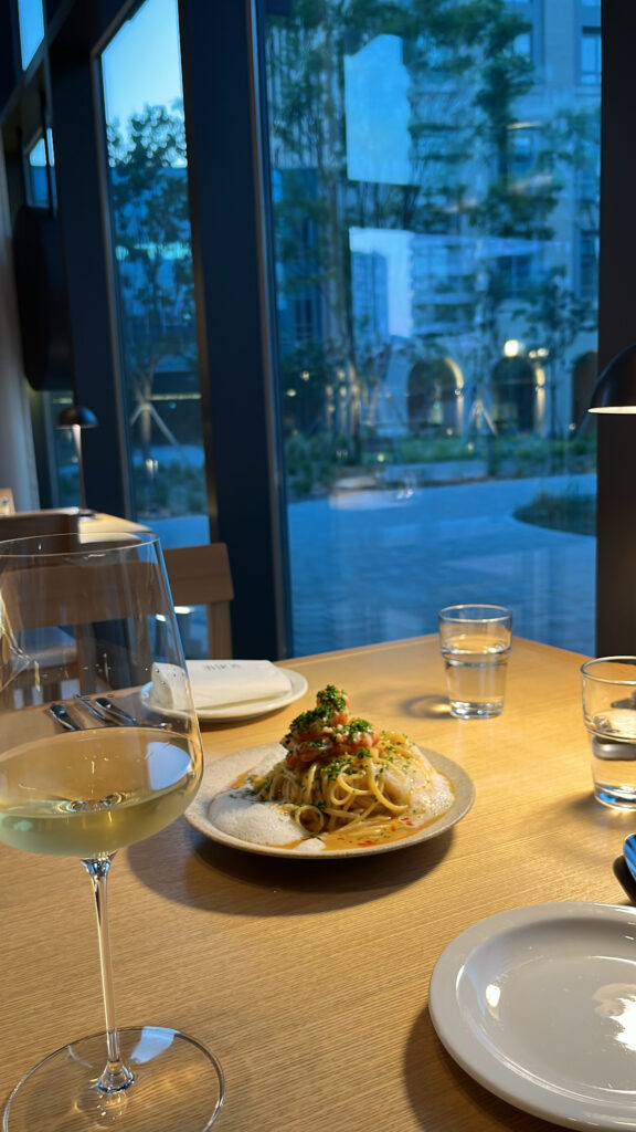 Dining table setup with wine glass overlooking the lush outdoor garden pond through glass windows