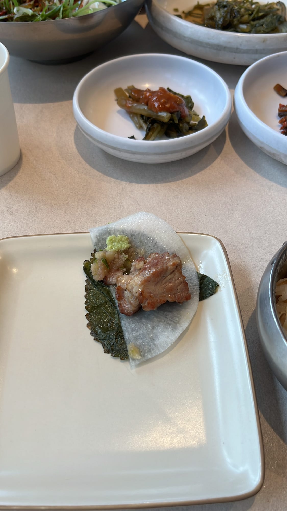 Delicious bite of grilled pork wrapped with savory pickled leaf at Gohasoon Gwangalli
