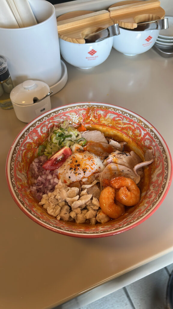 Close-up of Ebi Miso Abura Soba featuring shrimp oil, toppings, and thick noodles
