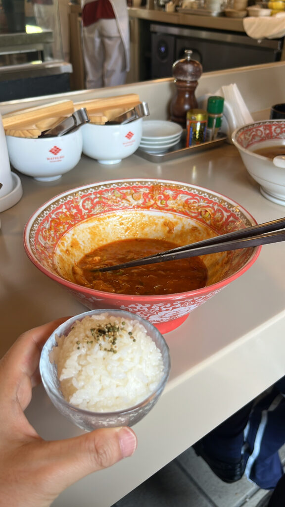 Mixing complimentary rice into remaining spicy abura soba sauce at Matsudo Busan