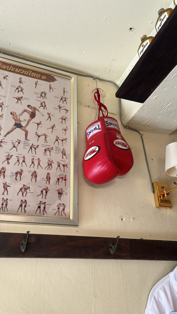 Muay Thai boxing gloves and retro Thai calendar posters adorning the interior wall