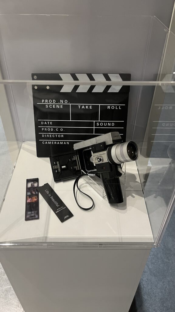 Vintage clapperboard and 8mm film camera displayed in a glass showcase at the library