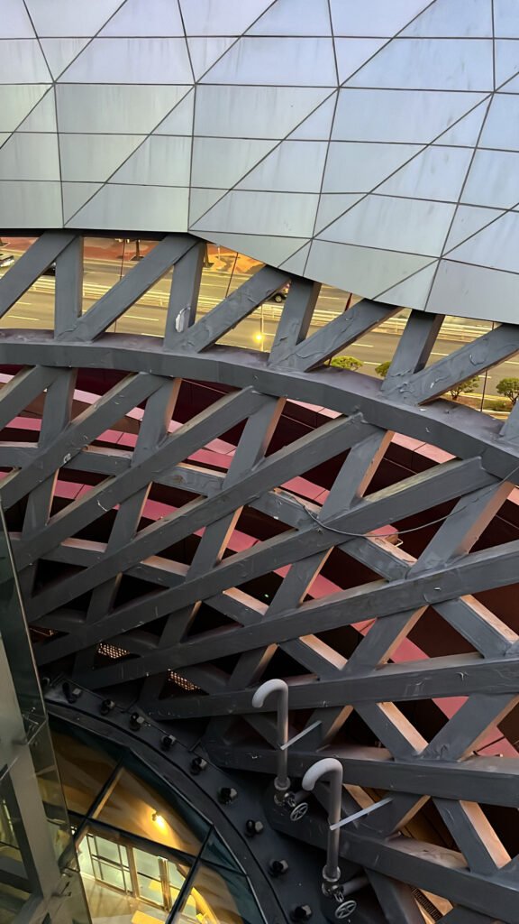 Close-up of the intricate mesh ceiling structure under the giant cantilever roof