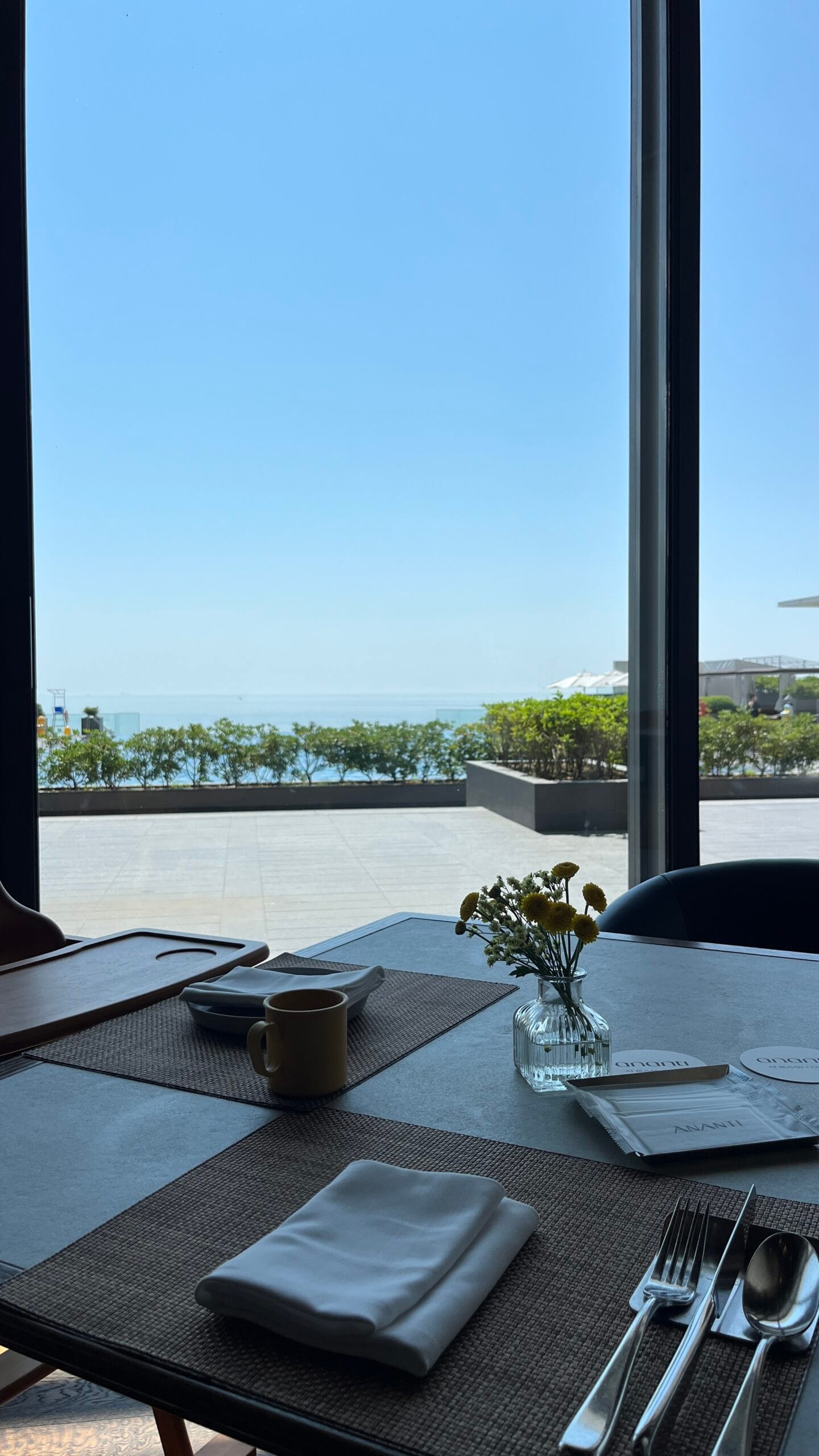 Mesas junto a la ventana con vistas panorámicas al mar durante el desayuno en Ananti Cove