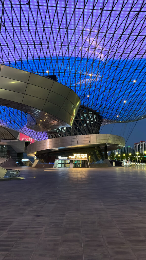 Atmospheric night view of the illuminated Double Cone and library entrance plaza