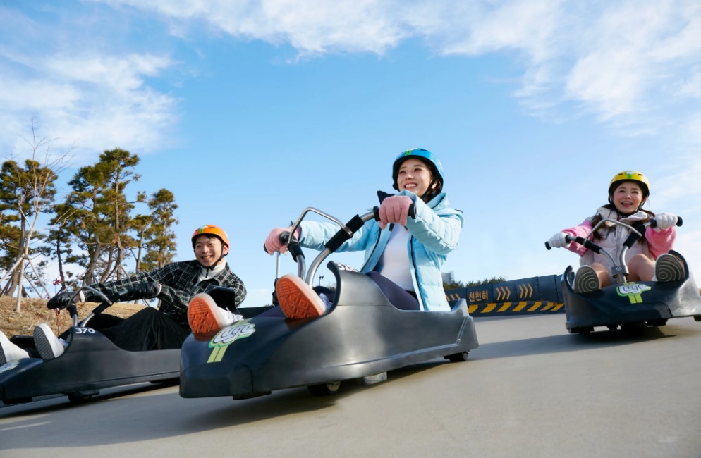 People riding downhill luge carts at Skyline Luge Busan in Gijang