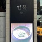 Sleek black exterior signboard and illuminated pork soup display at Anmok Busan