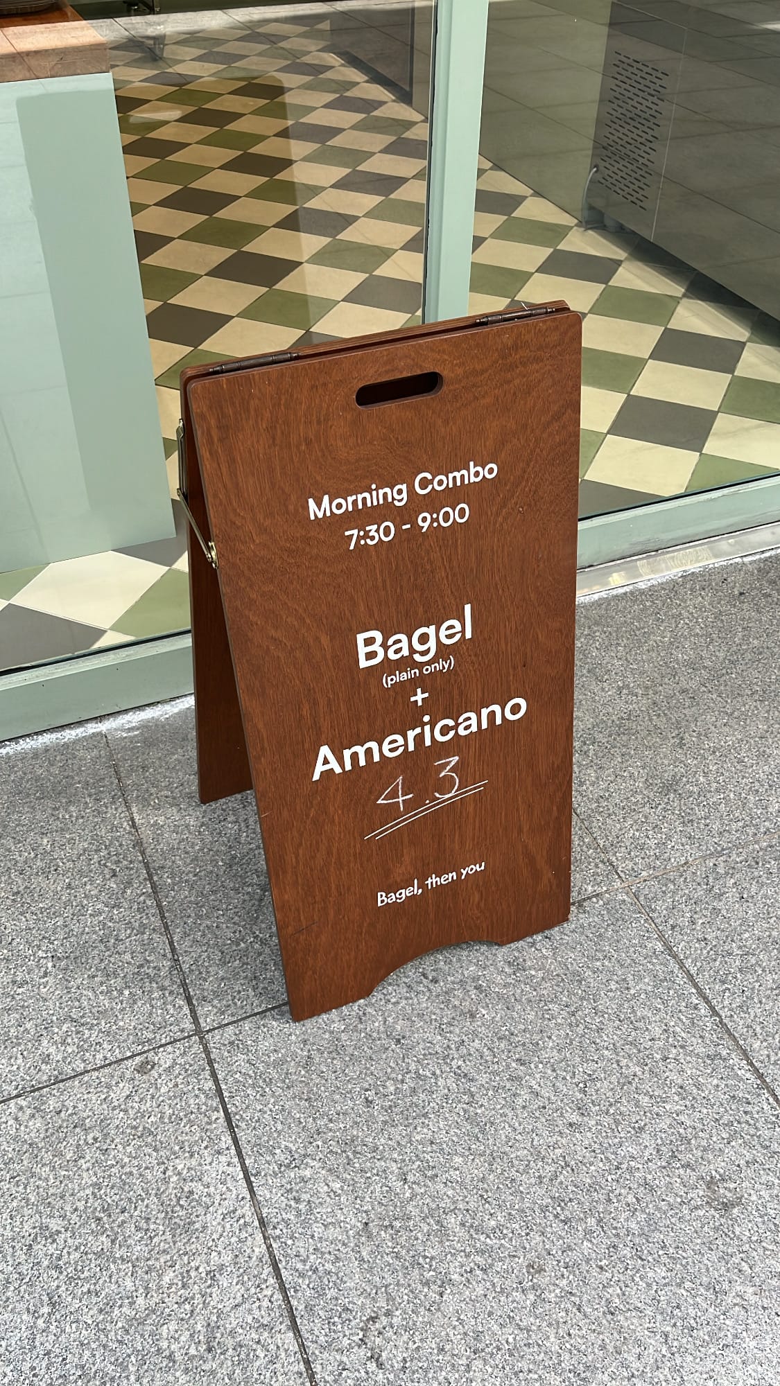 Wooden sidewalk sign announcing the Morning Combo special at Bagel Then You Busan Centum